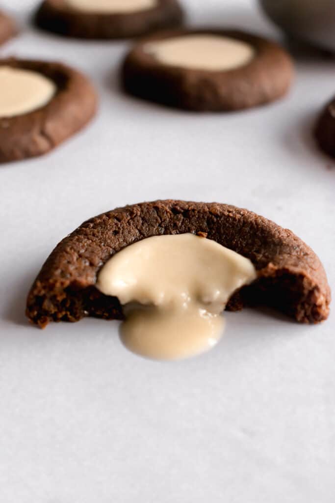 One chocolate thumbprint cookie cut into half with tahini pouring out
