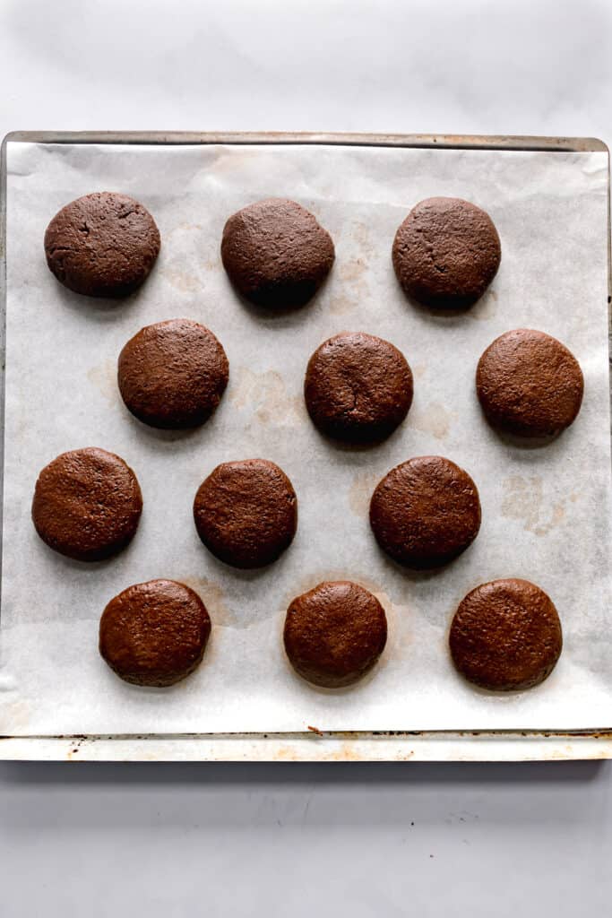Chocolate cookies shaped in 1 inch balls on a lined baking tray